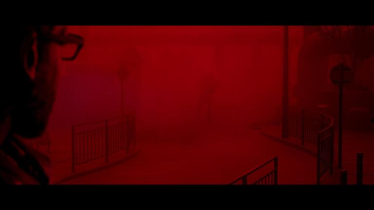 Il protagonista di Silent Hill: Townfall osserva una figura oscura immersa in una fitta nebbia rossa